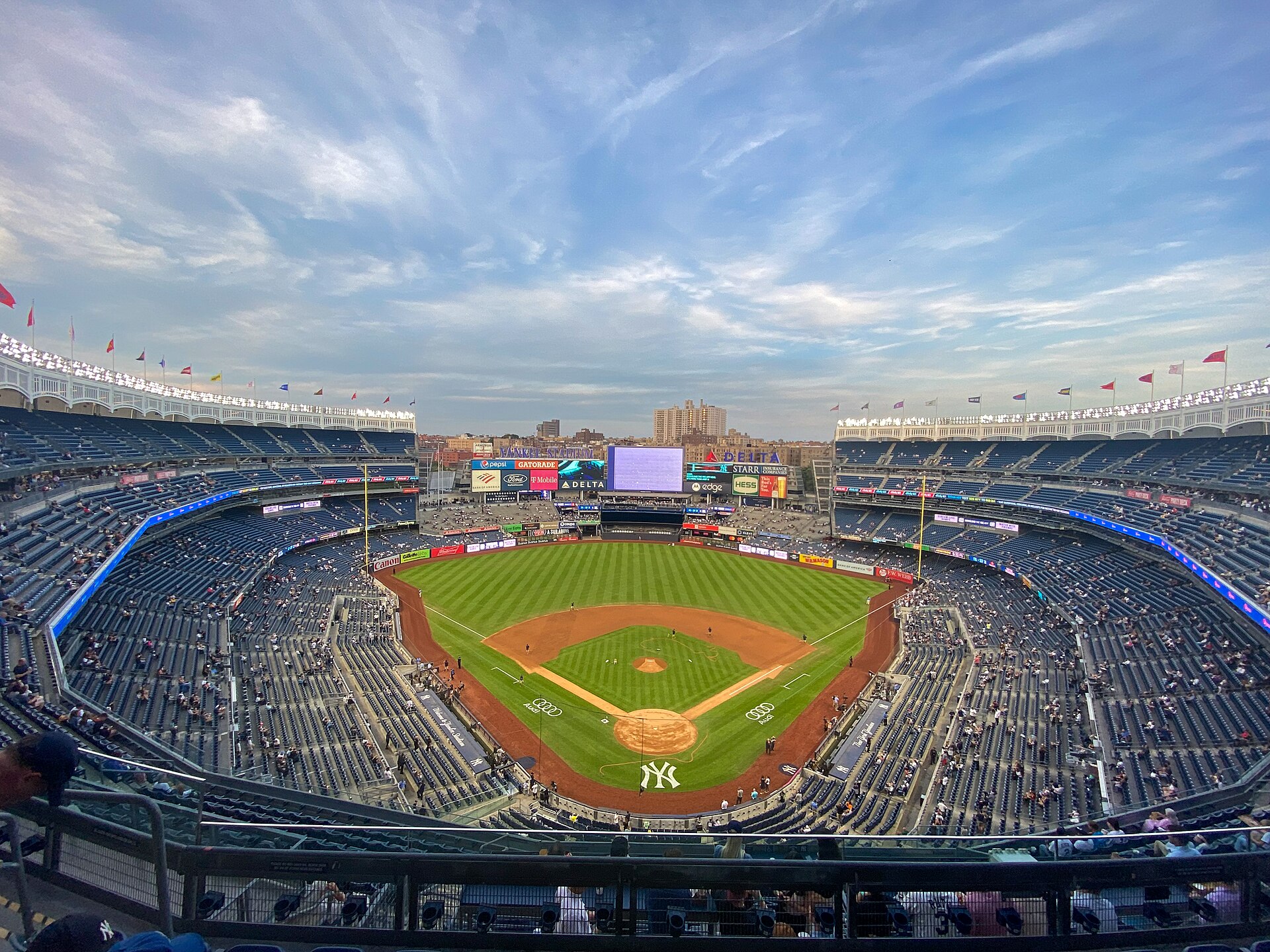 Yankee Stadium seen from the upper deck behind home plate, with the field lit before a night game